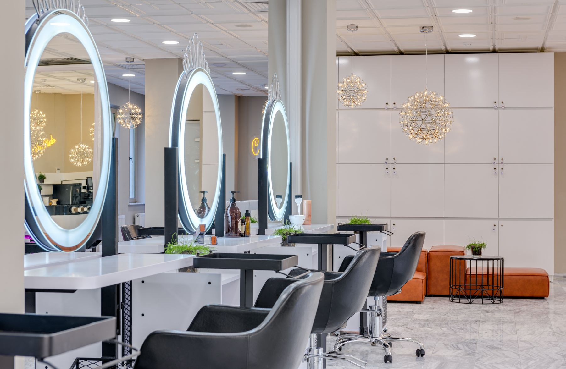 Bright salon with leather chairs and round lit mirrors
